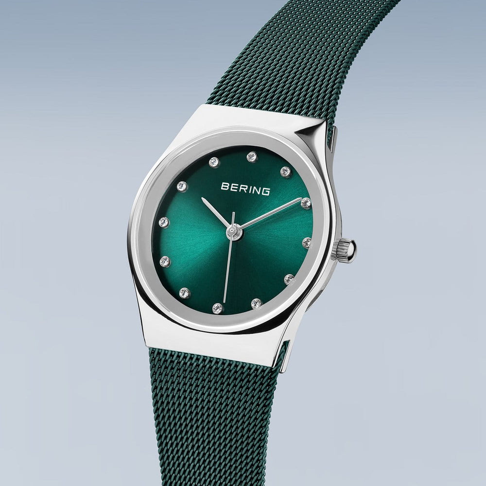 Het Bering 12927-808 horloge heeft een zilveren kast met een metallic groene wijzerplaat en Milanees bandje. Het beschikt over een nauwkeurig quartz uurwerk, zilveren edelsteenachtige uurmarkeringen en wijzers, plus het elegante Bering logo op een lichte gradiënt achtergrond.