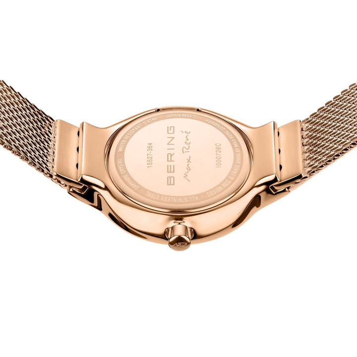Een close-up van het Bering 15527-364-GWP horloge toont een roségouden mesh band en gegraveerde tekst zoals BERING en een handtekening op de achterkant. Dit quartz-uurwerk heeft een ronde kast, zijkroon en duurzaam saffierglas.