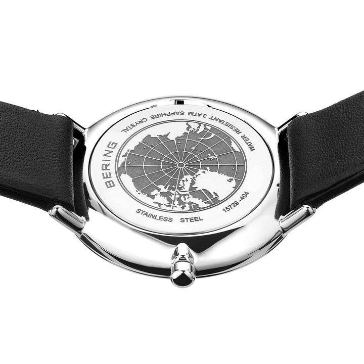 De achterkant van Berings dameshorloge 15729-404 toont een kaartontwerp met BERING, WATER RESISTANT 5ATM en SAFFIERGLAS gravures. Het heeft een quartz-uurwerk voor precisie, een zwarte band en een glanzende metalen kast.