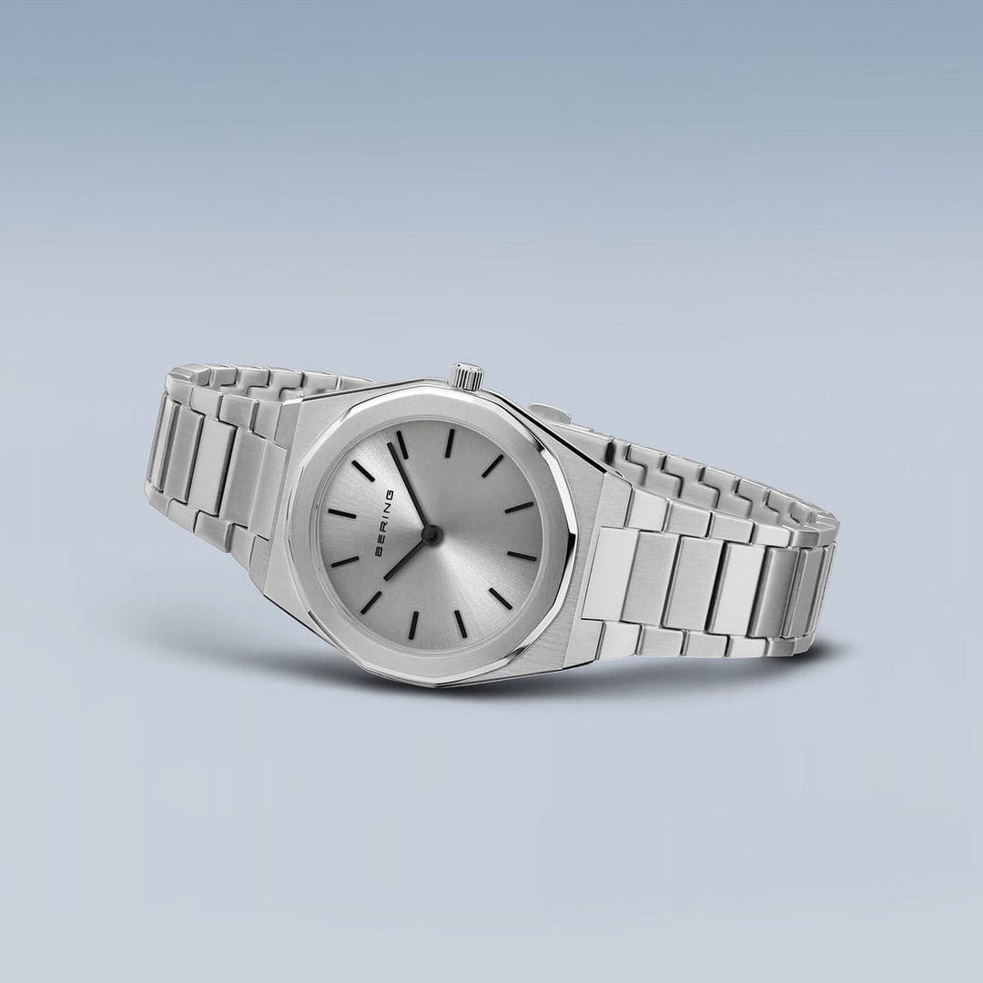 Het Bering dames horloge zilveren dial - 19632-700 heeft een strak zilveren design met een metalen band, minimalistische ronde wijzerplaat, eenvoudige zwarte wijzers en een kleine kroon. Het heeft een nauwkeurig quartz uurwerk en een zachte gradiënt lichtblauwgrijze achtergrond.