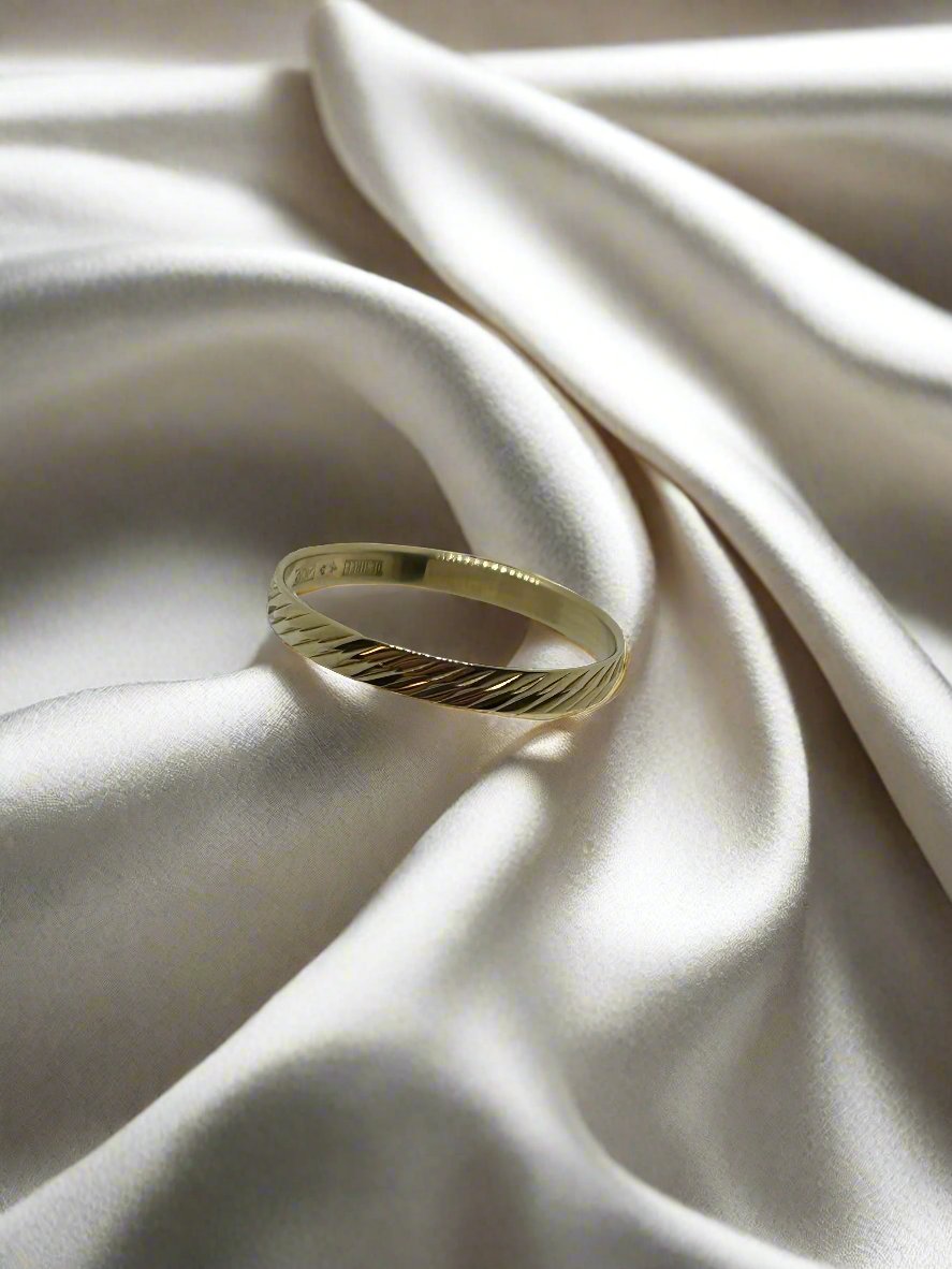 Vintage Ring aus 14k Gold mit gewelltem Design auf einem satinartigen Hintergrund