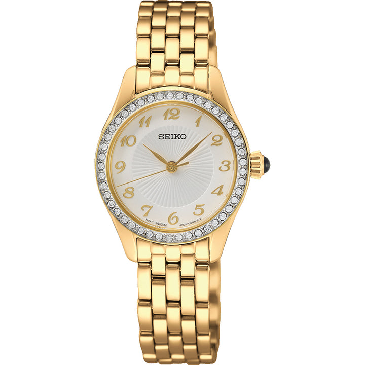 Het Seiko dameshorloge SUR388P1 is een prachtig gouden polshorloge met een ronde wijzerplaat, witte wijzerplaat met gouden Arabische cijfers en heldere stenen op de lunette. Het heeft een quartz uurwerk en gouden schakelband, geaccentueerd door een groene steen op de kroon voor extra elegantie.