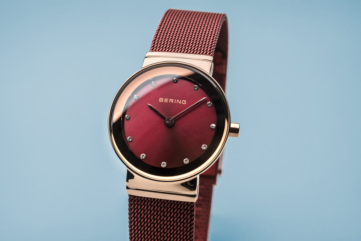 Uhr mit rotem Zifferblatt, goldfarbenem Gehäuse und rotem Mesh-Armband