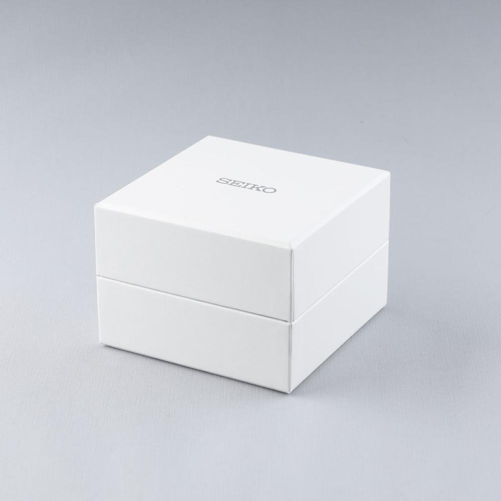 Op een lichtgrijze achtergrond staat een wit vierkant doosje met de tekst Seiko in het grijs. Hierin zit een Seiko dameshorloge SUR549P1 met een quartz uurwerk en Hardlex mineraal glas.