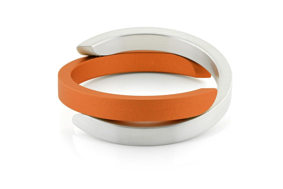 De Armband Cs beschouwd Oranje A1O van CLIC Creations combineert moderne stijl met twee in elkaar verweven banden: een metallic zilveren en een matte oranje. Handgemaakt in Nederland, het minimalistische design en de gladde afwerking creëren een eigentijdse, stijlvolle look.