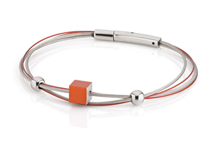De Armband kubusje Oranje A230O van CLIC Creations is een strak accessoire met verweven rode en zilveren kabels, handgemaakt in Nederland. Het toont een centrale oranje kubus met twee zilveren bolvormige accenten en heeft een stijlvolle bajonetsluiting voor bevestiging.