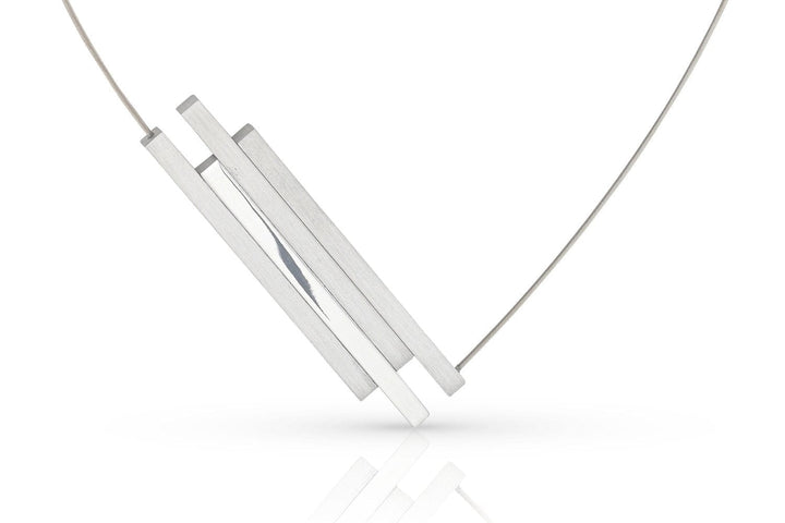 De C264-ketting van Clic Creations heeft een minimalistisch ontwerp met drie dunne, rechthoekige zilveren staafjes die aan een fijne ketting zijn bevestigd. Hierdoor ontstaat een geometrische en eigentijdse look tegen een witte achtergrond.