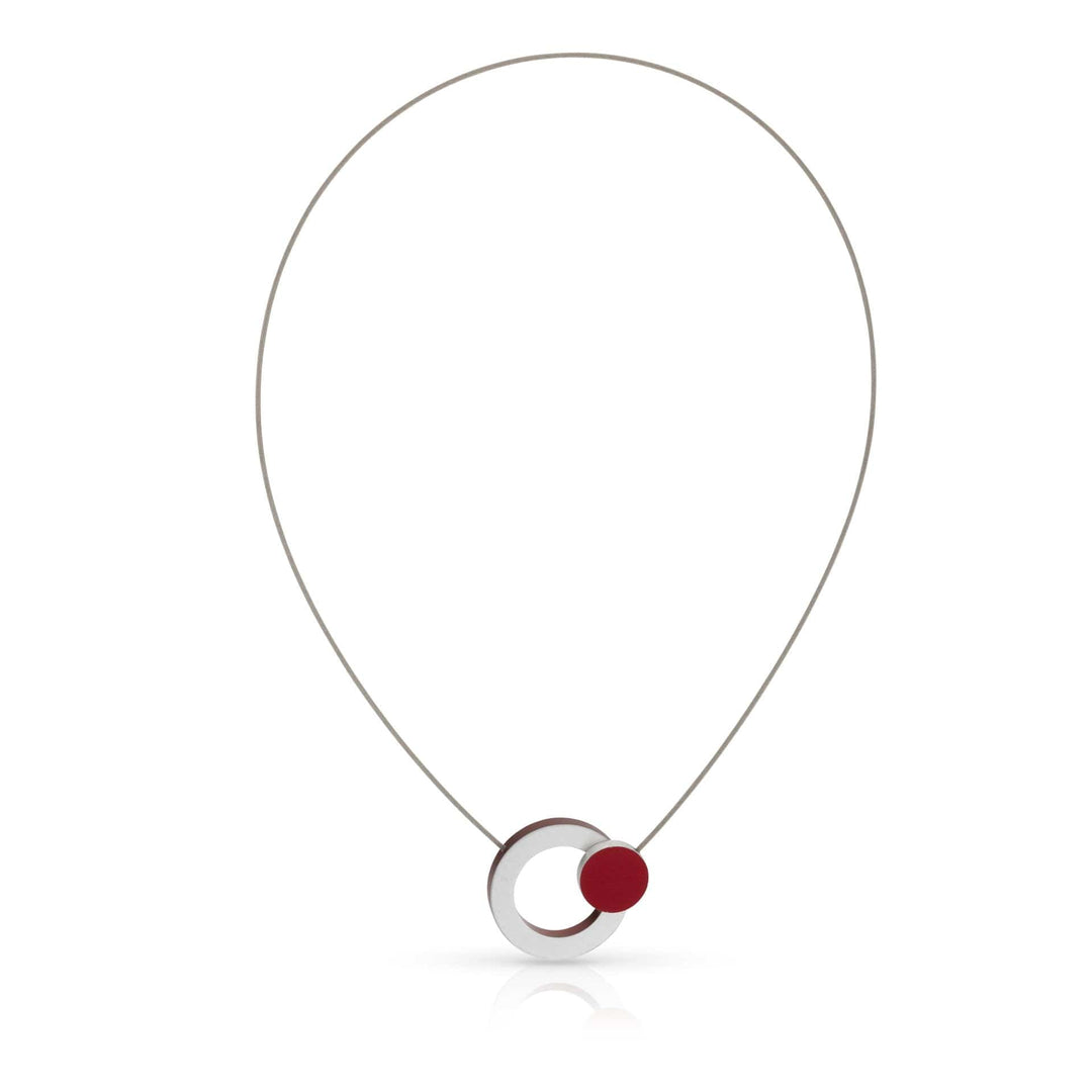 De Collier Ring met rood rondje C270R van CLIC Creations heeft een minimalistisch ontwerp met een dunne zilveren draad en een ronde hanger van overlappende cirkels in zilver en rood. Dit moderne stuk is handgemaakt in Nederland en heeft een glad reflecterend oppervlak en een magnetische sluiting.