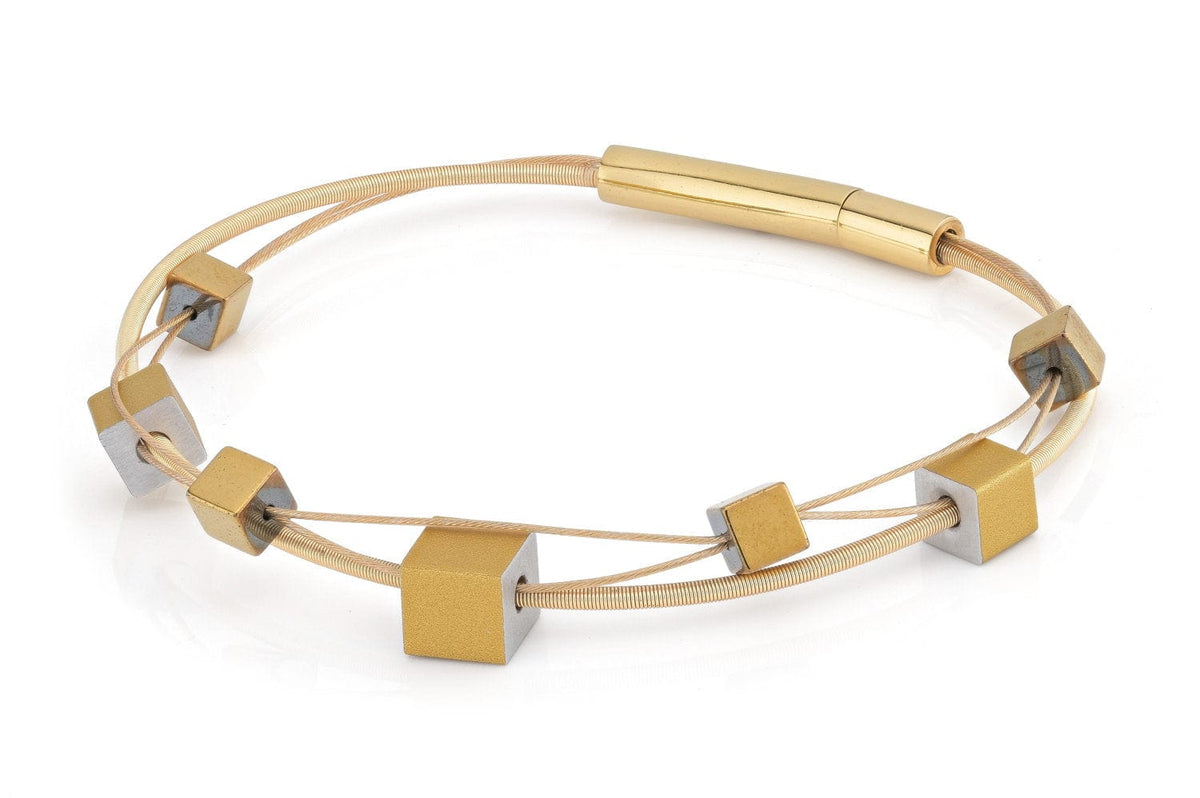 Armband mit goldfarbenen und silberfarbenen Kubusformen auf einem flexiblen Band